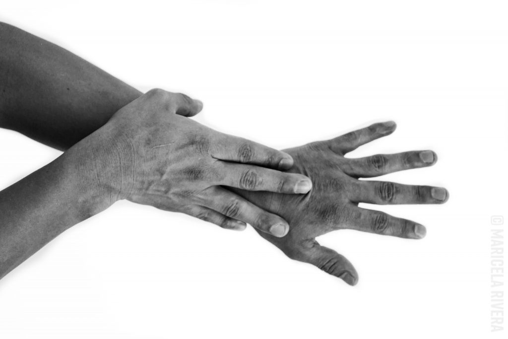 En blanco y negro. Son dos manos, la una se ve sobrepuesta desde la muñeca hacia arriba. En una apariencia de manos en secuencia.
